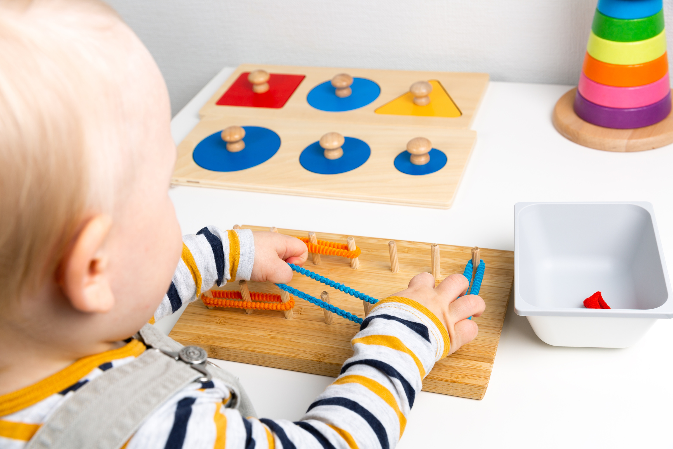 Child works with Montessori material for fine motor skills, sensory play. Playing children